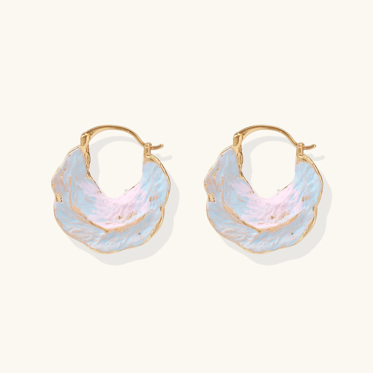 Shell-shaped hoop earrings with iridescent blue-pink enamel and gold trim on cream background