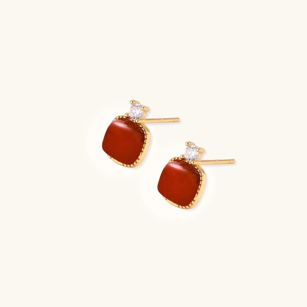 18K gold vermeil stud earrings with cushion-cut red agate stones and sparkling crystal accents on beige background
