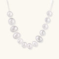 Graduated pearl-finish silver discs forming an organic bubble bib necklace on delicate chain against cream background.