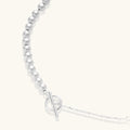 Long sterling silver beaded necklace with graduated sphere design, toggle clasp, and delicate chain extension on white background