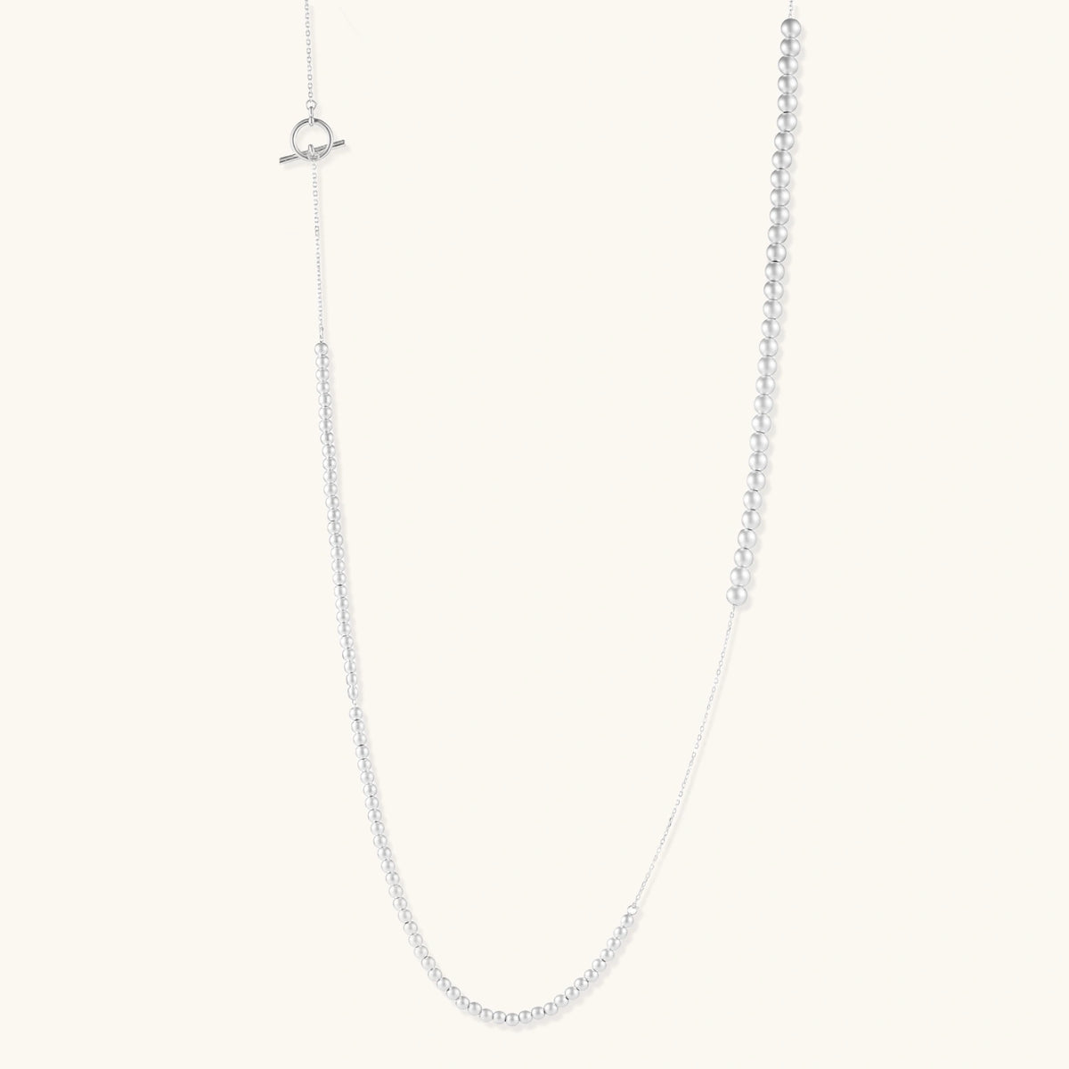 Long sterling silver beaded necklace with graduated sphere design, toggle clasp, and delicate chain extension on white background