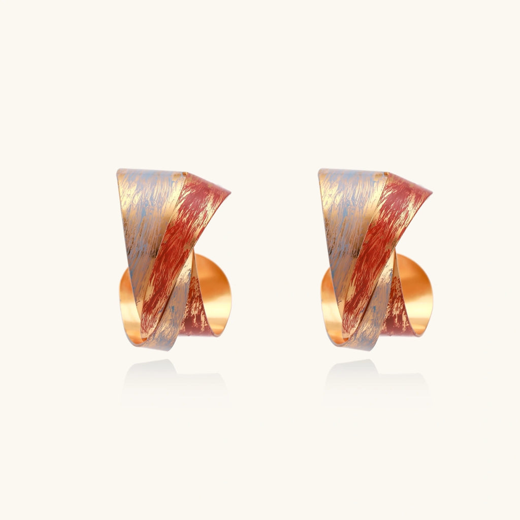 Sculptural gold-plated hoop earrings with diagonal purple and coral enamel stripes in twisted ribbon design