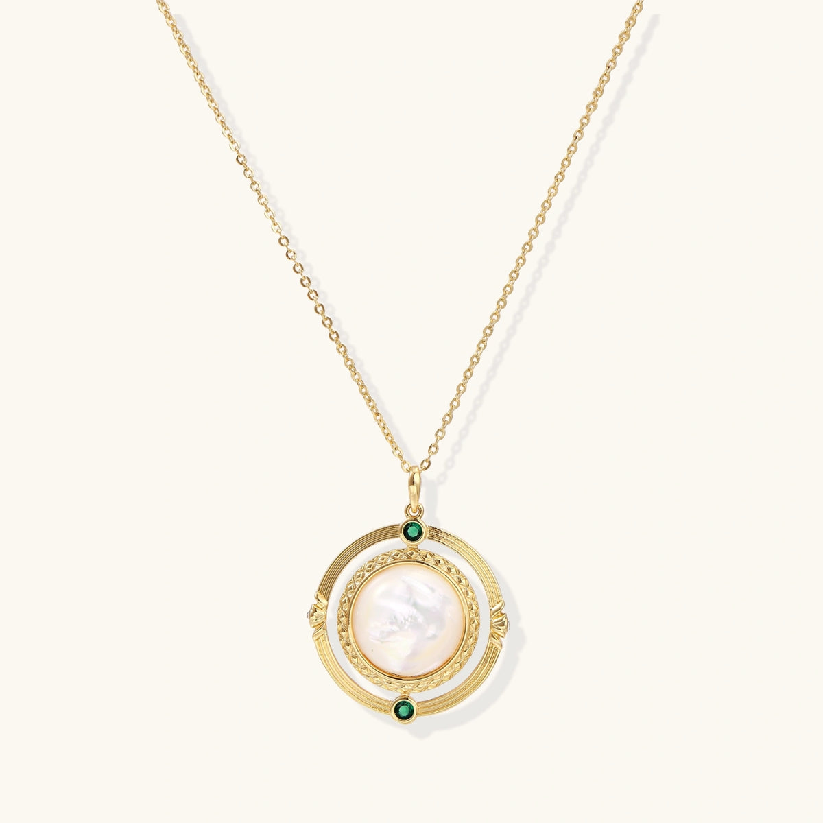 Gold pendant necklace with circular orbital design, iridescent mother-of-pearl center, and green zirconia accents