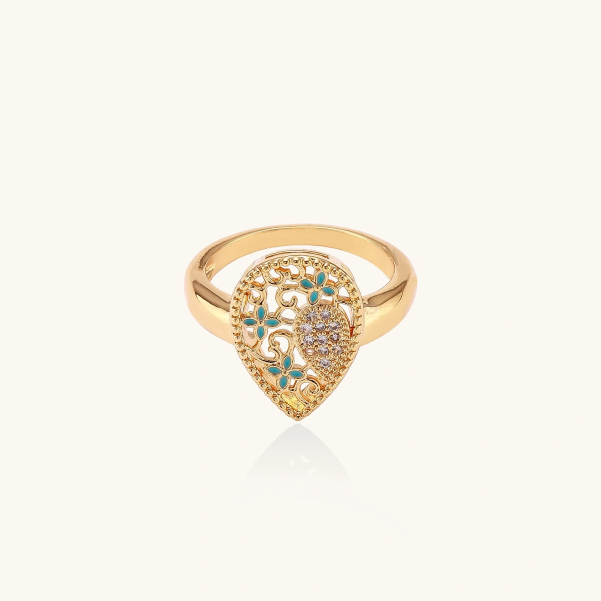 Teardrop-shaped gold-plated ring with turquoise enamel flowers and crystal pavé detail on cream background