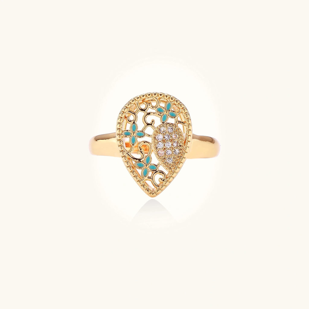 Teardrop-shaped gold-plated ring with turquoise enamel flowers and crystal pavé detail on cream background